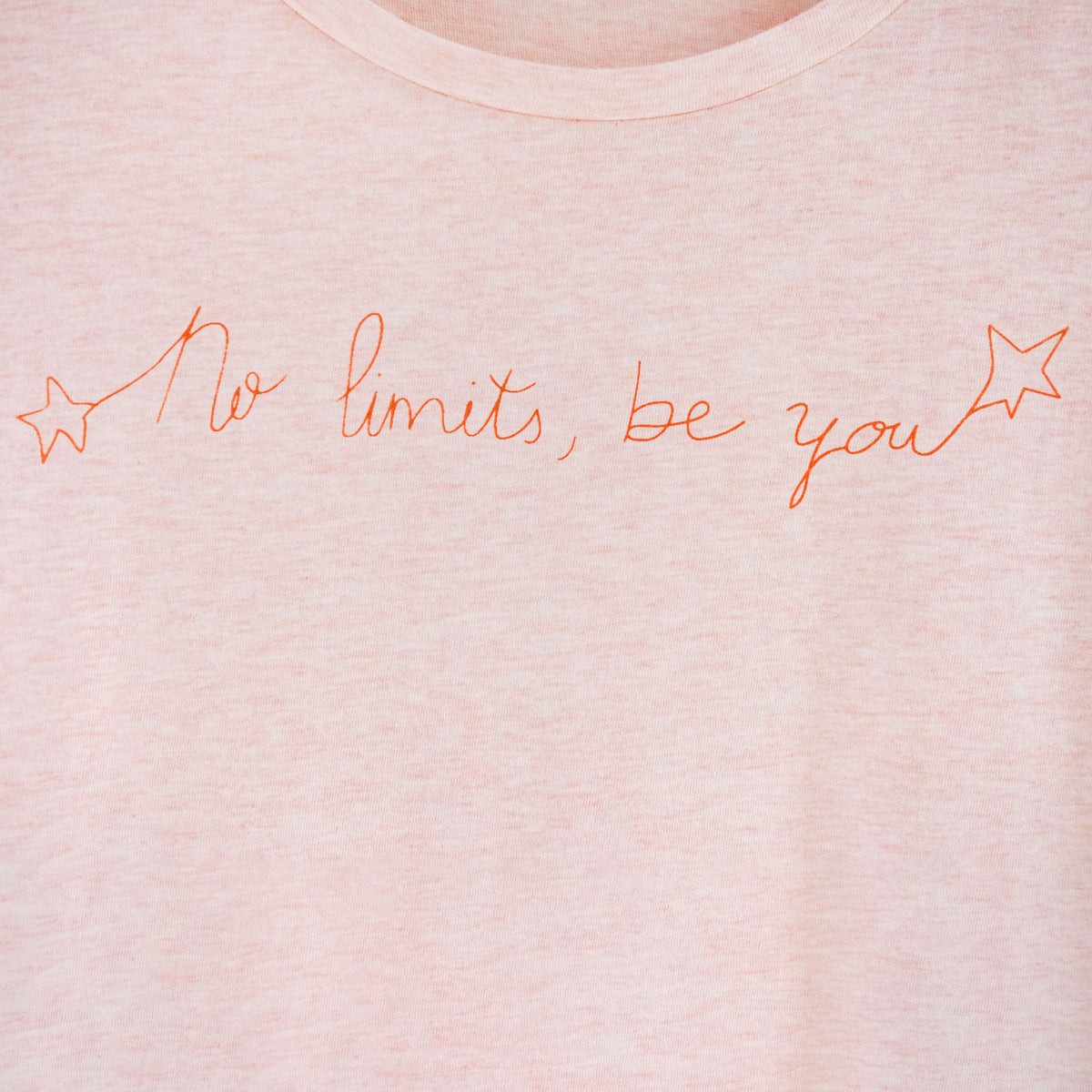 Detalle de texto estampado en color naranja. Camiseta rosa de mujer, de algodón orgánico y estampada a mano con tintas ecológicas.