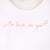 Detalle de texto estampado en color naranja. Camiseta blanca de mujer, de algodón orgánico y estampada a mano con tintas ecológicas.