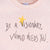 Detalle de texto serigrafía en color negro, y amarillo. Camiseta rosa de algodón orgánico para niños, estampado a mano con tintas ecológicas. Modelo unisex.