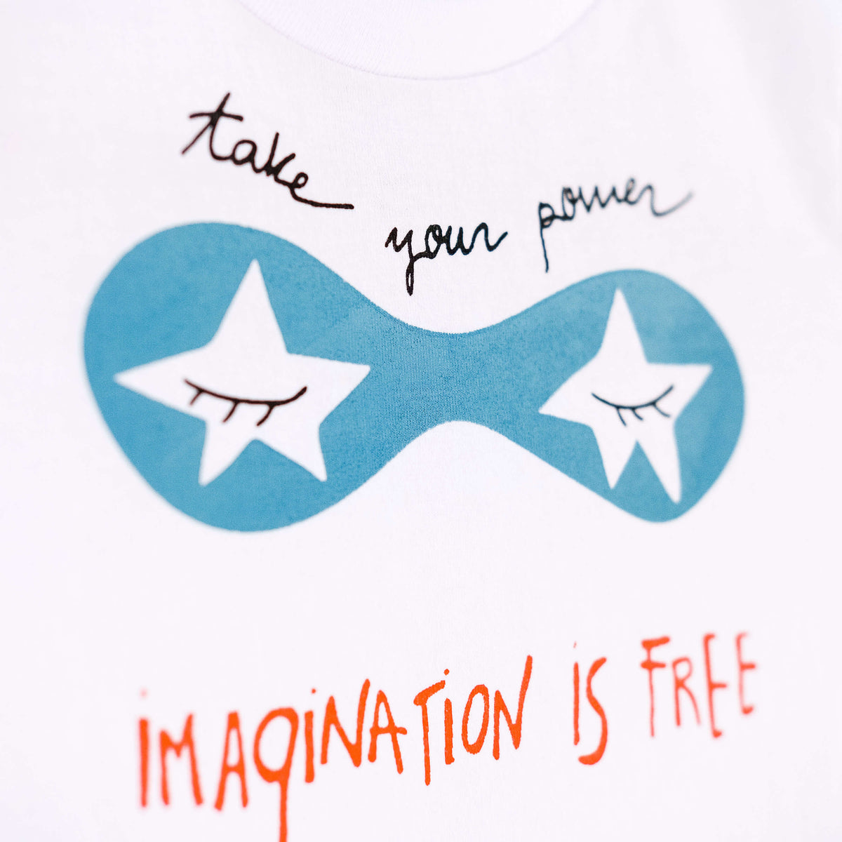Detalle de texto serigrafía en color negro, azul y naranja. Camiseta blanca de algodón orgánico para niños, estampado a mano con tintas ecológicas. Modelo unisex.