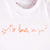 Detalle de texto estampado en color naranja. Camiseta blanca de algodón orgánico para niños, estampado a mano con tintas ecológicas. Modelo unisex.