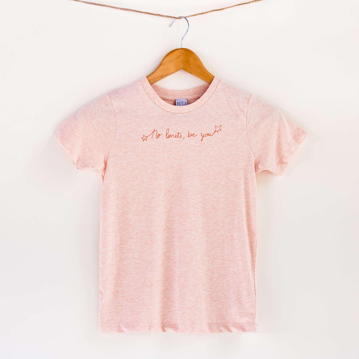 Camiseta rosa de algodón orgánico para niños, estampado a mano con tintas ecológicas. Texto estampado en color naranja. Modelo unisex.